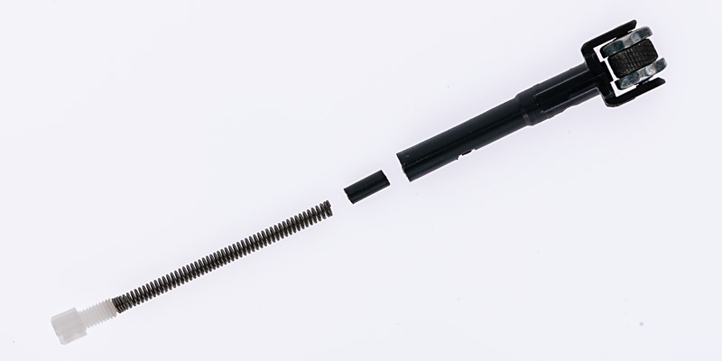 Ein Clipper-Feuersteinhalter in Einzelteilen vor weissem Hintergrund. Die Bestandteile sind der schwarze Halter mit Reibrad, eine Metallfeder, ein kleiner Feuerstein und eine weiße Kunststoffkappe. Diese Anordnung zeigt, wie die Feuersteine in Clipper-Feuerzeugen ausgetauscht werden können.